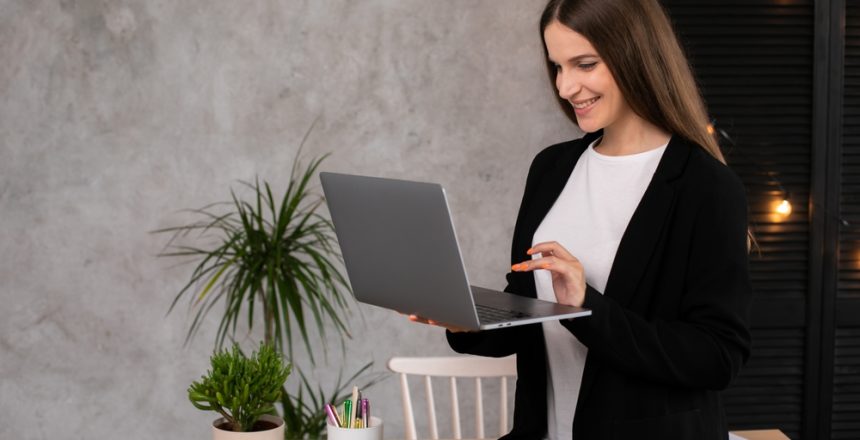 Smiling,Brunette,Woman,Using,Laptop,Computer,Over,Gray,Background.,Working