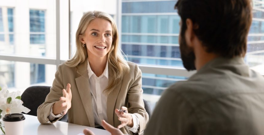Happy,Blonde,Young,Businesswoman,Talking,To,Business,Partner,At,Office